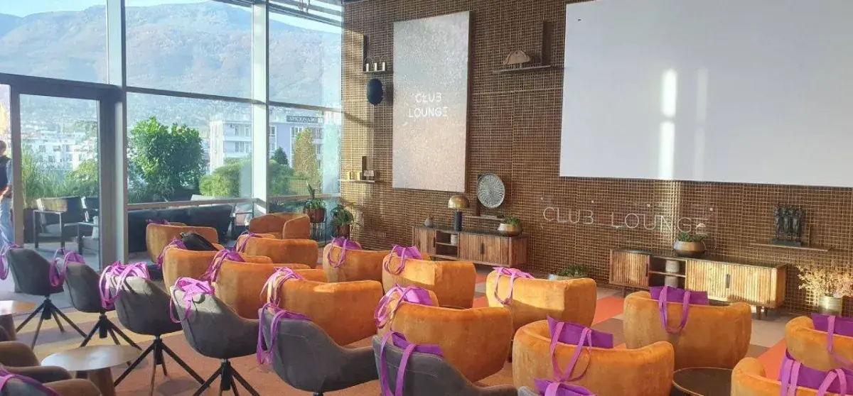 Room with view over city, Club Lounge sign on the wall, lots of empty chairs lined up facing the front with bags on them